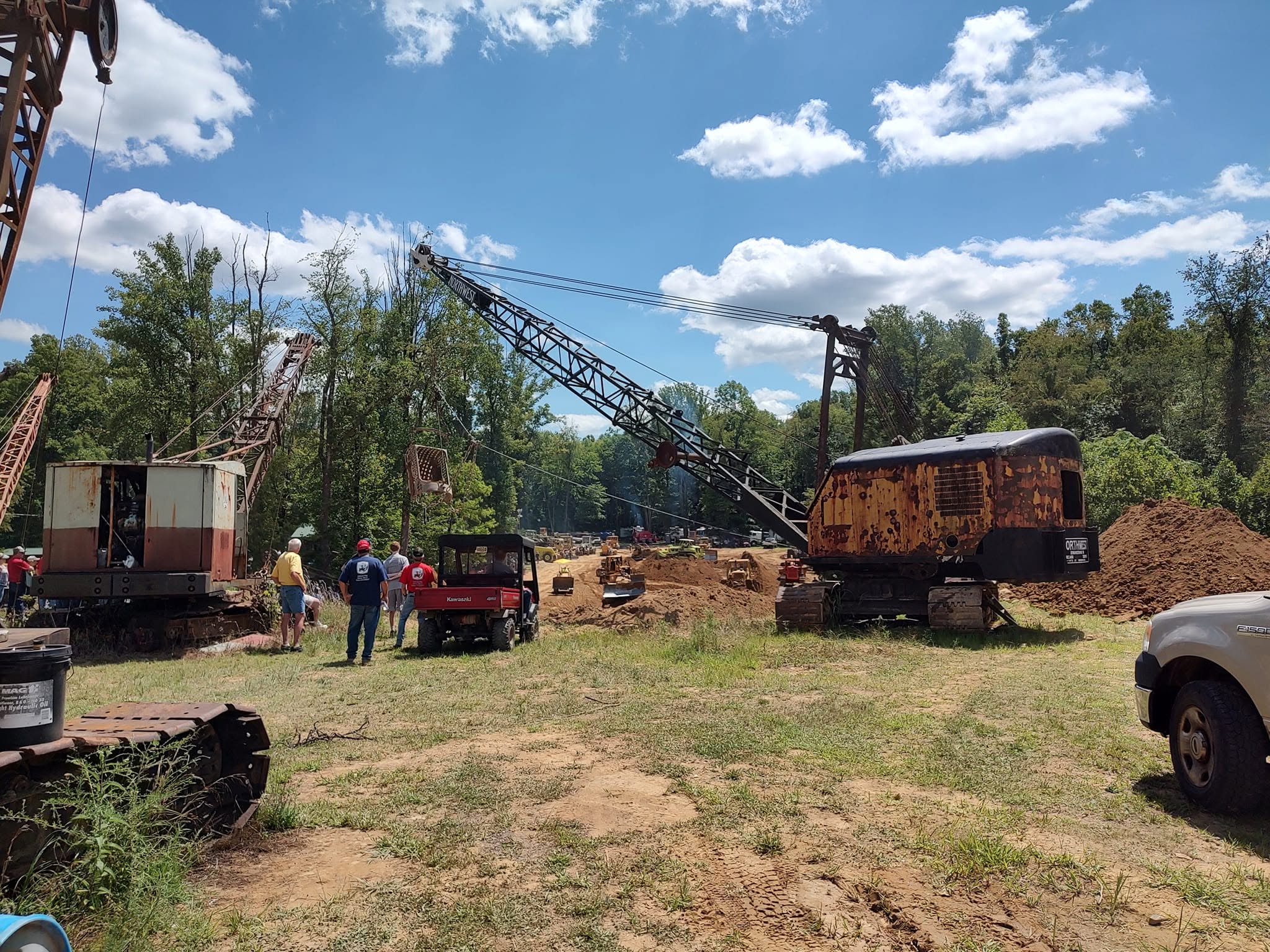 Large vintage cable-operated dragline crane on display with other machinery in the background